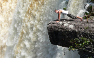 an image of a man doing press ups next to a big waterfall in the Guyana jungle
