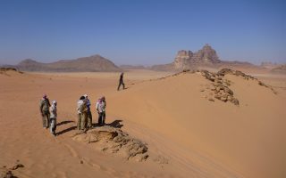an image of a group of people standing on a sand dune on the Bushmasters desert venture trip