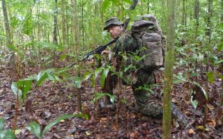 An image of a man wearing army gear crouching in the forest during a Bushmasters Jungle Combat venture