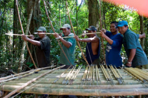 Men practicing at shooting their homemade arrows and smiling during their jungle survival course
