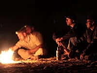 an image of four men sat, trying to light a campfire on our jungle survival trip
